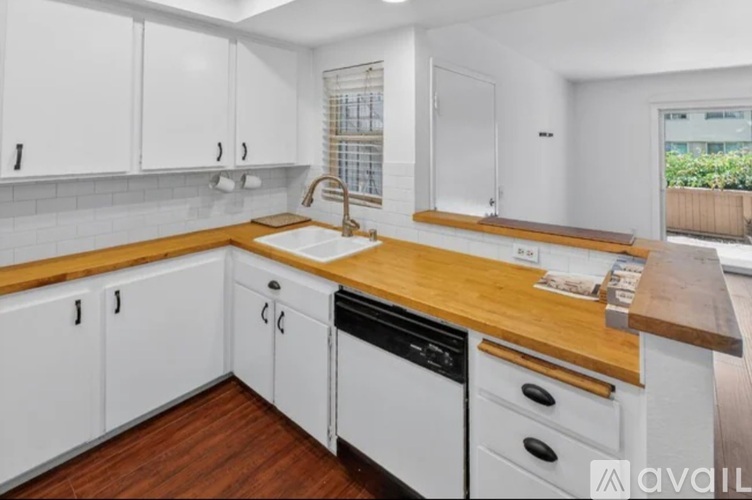 A kitchen with white cabinets and a wooden countertop.