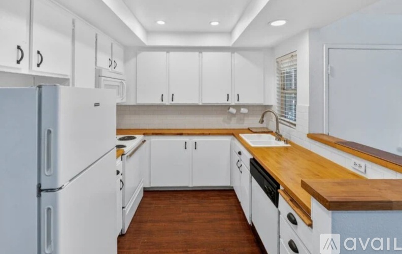 A kitchen with white cabinets and a wooden countertop.