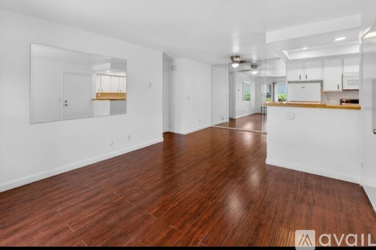 A spacious room with wooden flooring and white walls.