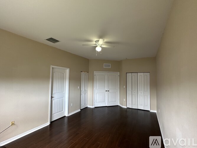 A spacious room with a ceiling fan and wooden floors.