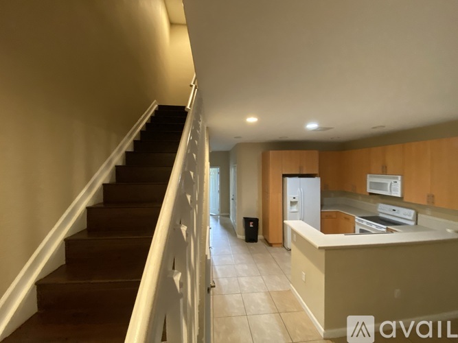 A staircase with a white railing leads to a kitchen area with wooden cabinets and a countertop.