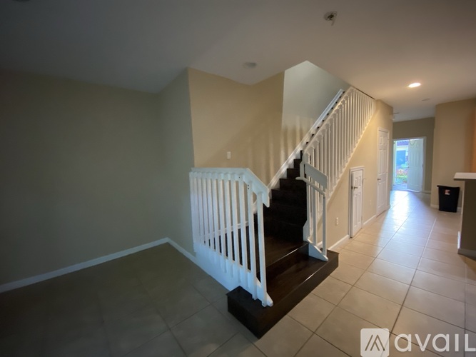 A spacious room with a staircase leading to the upper level.