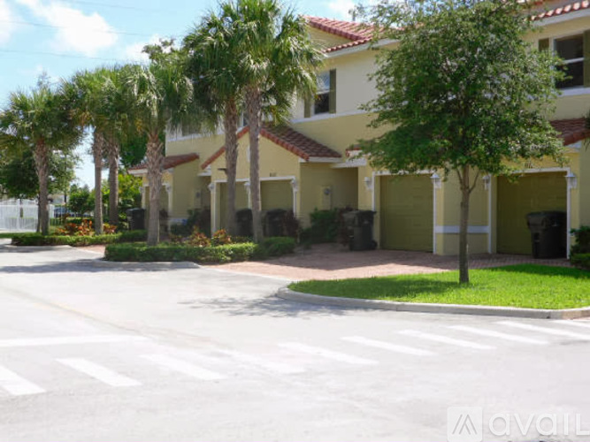 A row of palm trees in front of a yellow building.