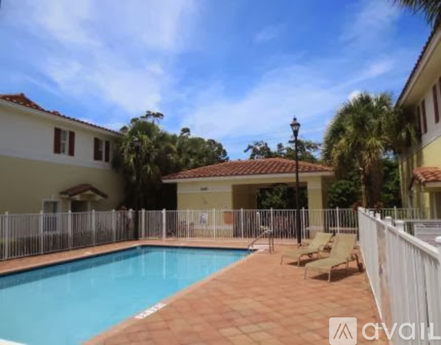 A pool surrounded by a white fence and a building in the background.