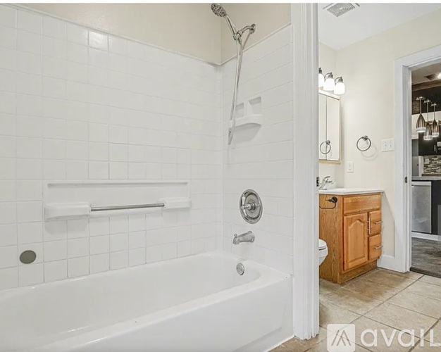A white tiled bathroom with a wooden cabinet and a bathtub.