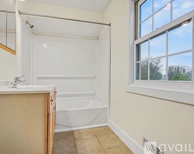 A bathroom with a tub, sink, and mirror.
