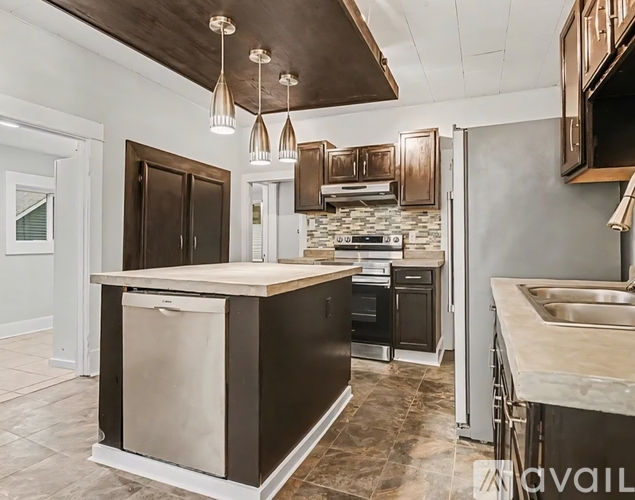A kitchen with a large island and dark brown cabinets.