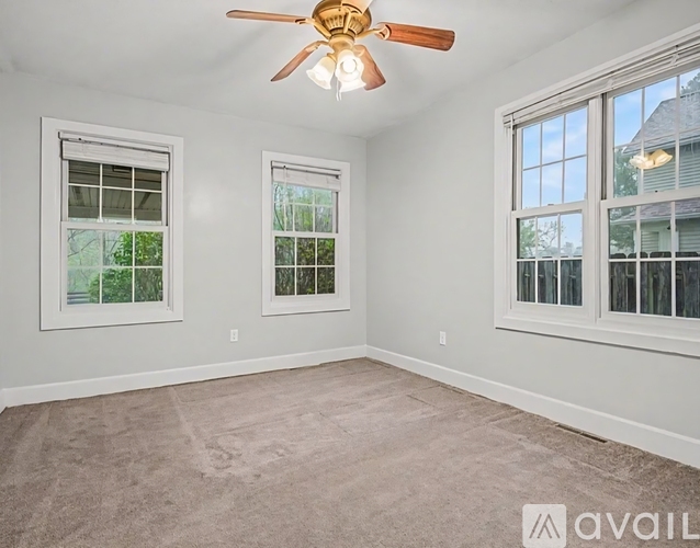 A room with a ceiling fan and two windows.