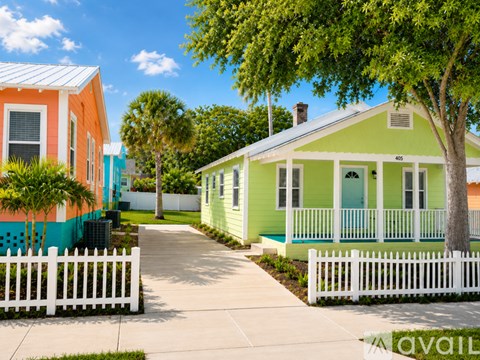A green house with a white picket fence in front of it.