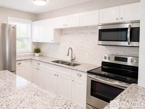 A modern kitchen with white cabinets and stainless steel appliances.