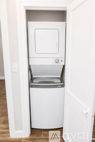A white compact washing machine is built into a cabinet.