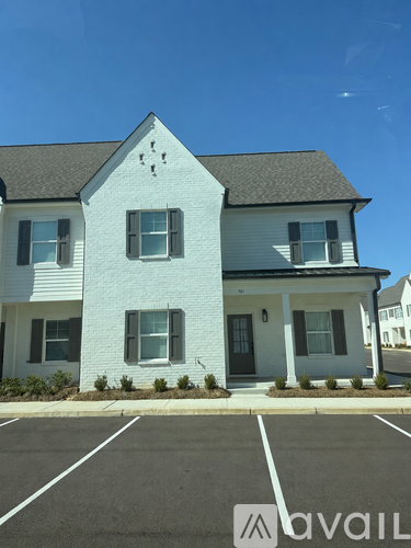A white house with a black door and windows is in front of a clear blue sky.