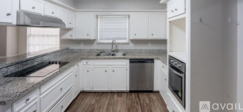 A kitchen with white cabinets and a granite countertop.