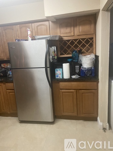 A stainless steel refrigerator in a kitchen with wooden cabinets.