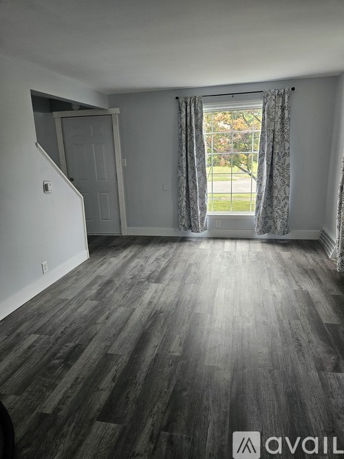 A room with a staircase and a window with curtains.