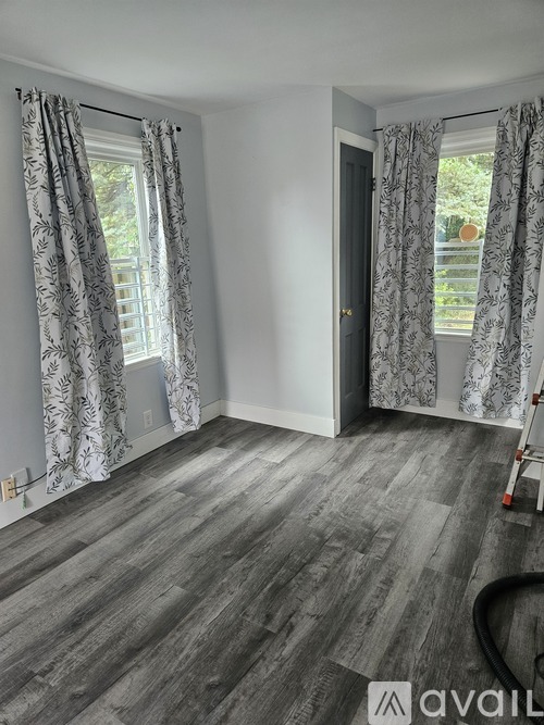 A room with grey flooring and patterned curtains.
