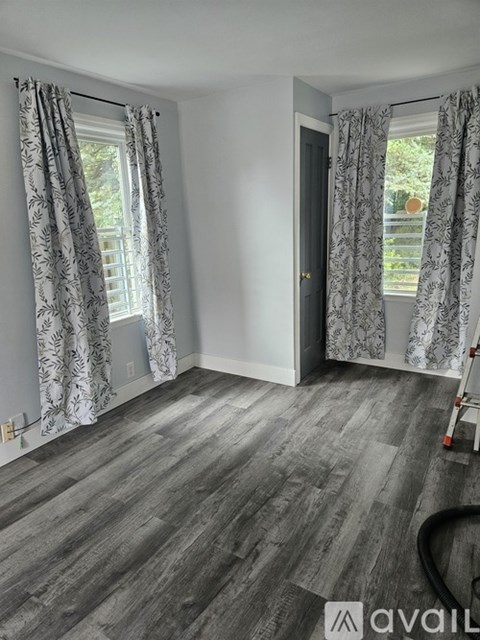 A room with grey flooring and patterned curtains.