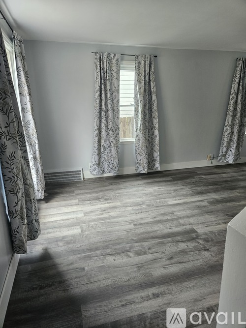 A room with wooden flooring and patterned curtains.