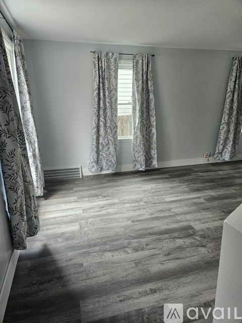 A room with wooden flooring and patterned curtains.