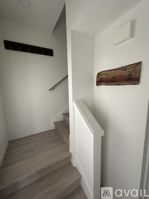 A staircase with a wooden handrail and a white wall with a wooden decoration.