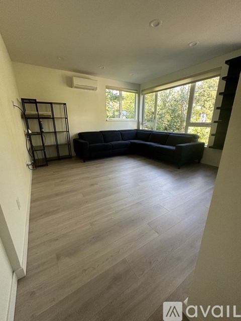 A living room with a black sofa and wooden flooring.