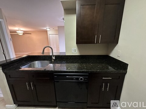 A kitchen with black cabinets and a black granite countertop.