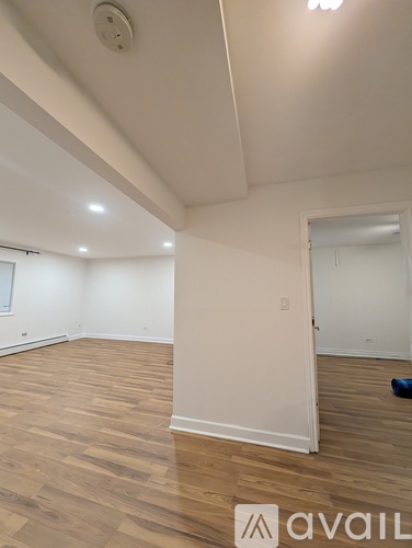 A room with wooden flooring and white walls.