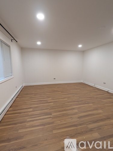 A room with wooden flooring and white walls.