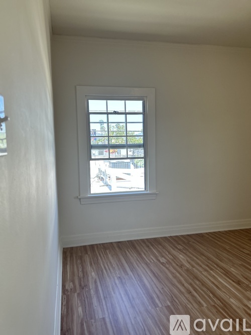 A room with a window and wooden flooring.
