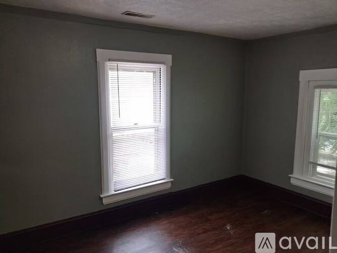 A room with a window and a wooden floor.
