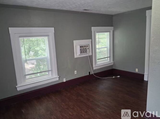 A room with two windows and a white electrical box on the wall.