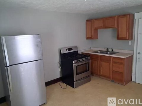 A kitchen with a stainless steel refrigerator, a stove, and wooden cabinets.