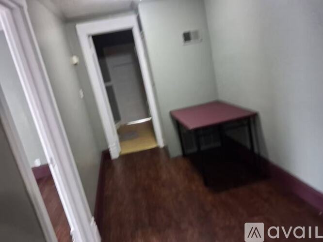 A room with a wooden floor and a red table.