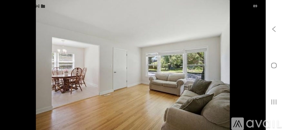 A spacious living room with a dining area visible through the open door.