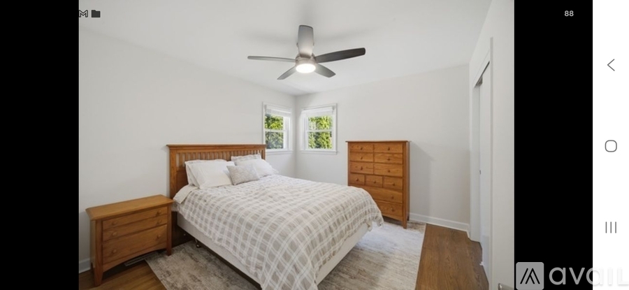 A bedroom with a bed, dresser, and ceiling fan.