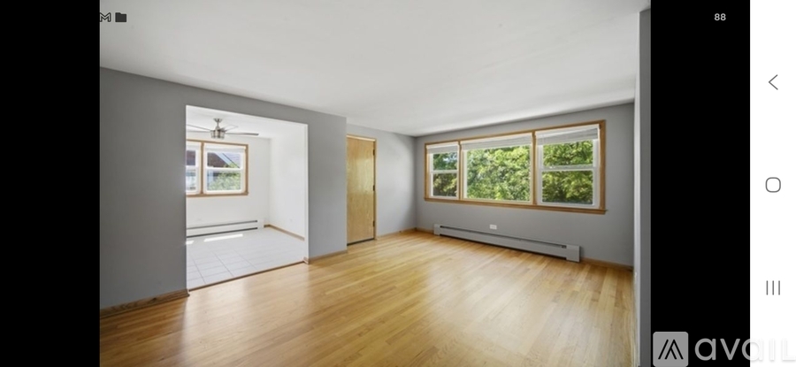 A spacious room with wooden floors and a large window.
