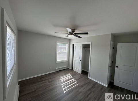A room with a ceiling fan and a window with blinds.