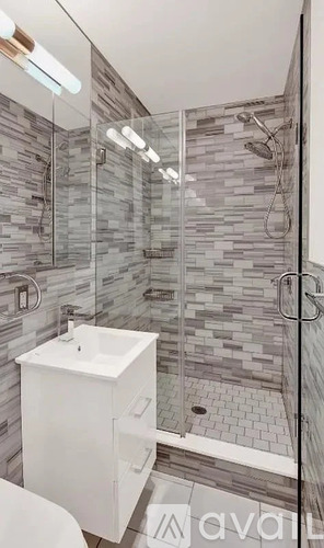 A modern bathroom with a walk-in shower and a white sink.