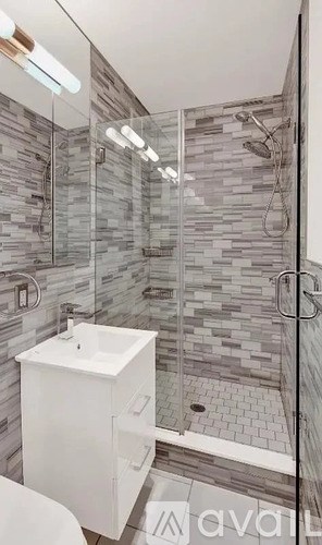 A modern bathroom with a walk-in shower and a white sink.