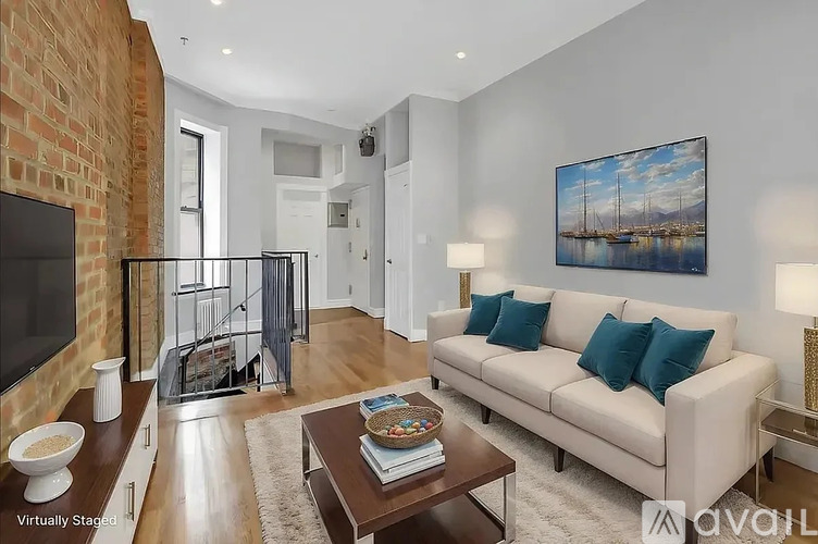 A living room with a white couch and a painting on the wall.
