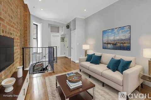 A living room with a white couch and a painting on the wall.