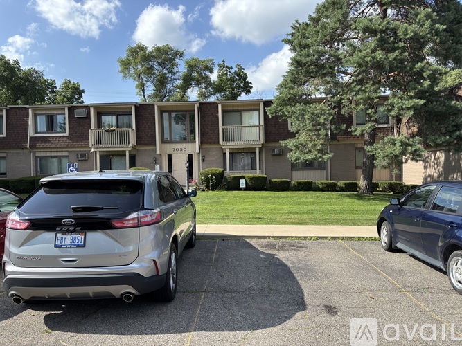 A silver SUV is parked in a parking lot in front of apartment buildings.