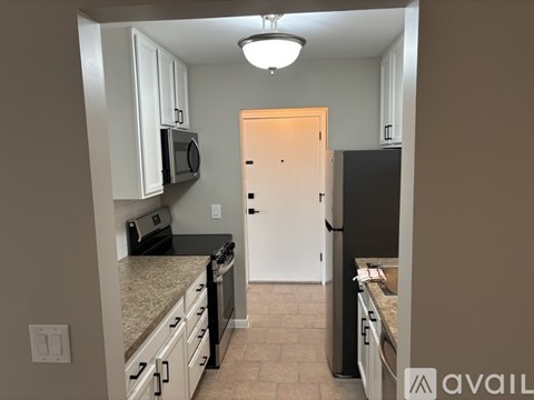 A kitchen with a black refrigerator and white cabinets.