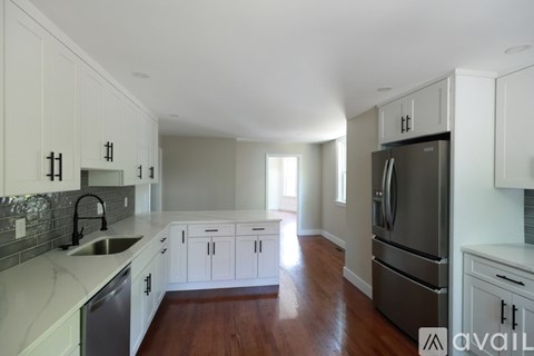A kitchen with white cabinets and a stainless steel refrigerator.