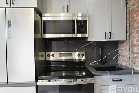 A modern kitchen with a stainless steel refrigerator, microwave, oven, and sink.