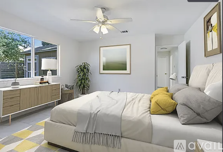 A bedroom with a white bed and a ceiling fan.