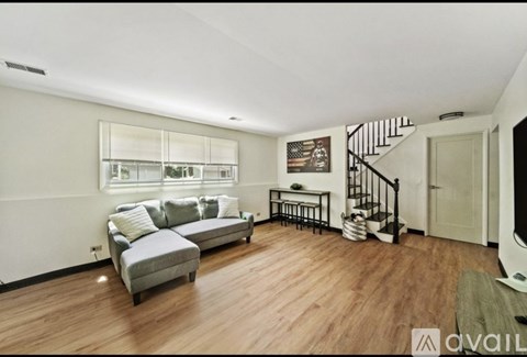 A living room with a grey sofa and a wooden floor.