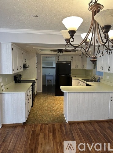 A kitchen with white cabinets and a black fridge.