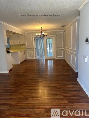 A spacious room with wood flooring and a chandelier.