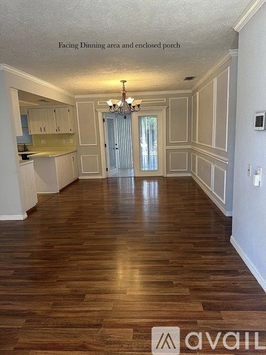 A spacious room with wood flooring and a chandelier.